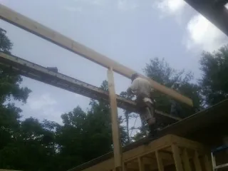 Carpenter setting a ridge beam over a new addition frame — Ice Dam Removal by Roofing Brothers in Little Orleans