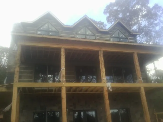 Dormers and porch framing on a large log home under construction — Roof Coating work by our crew in Little Orleans