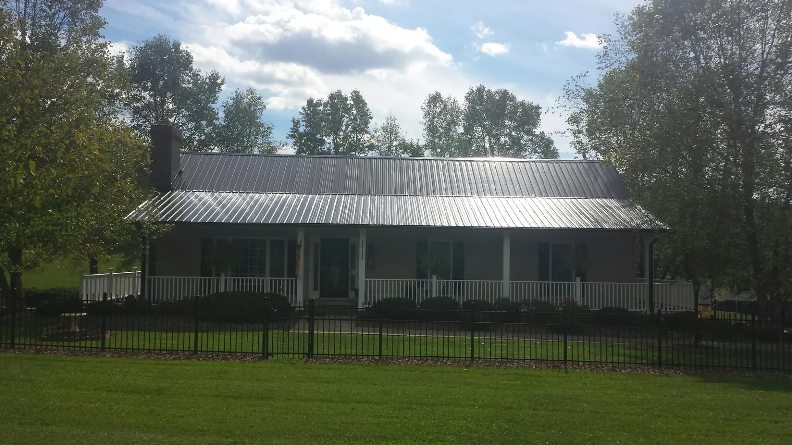 Gray metal roof on a brick ranch with a full width front porch — Gutter Guard Installation work by our crew in Little Orleans