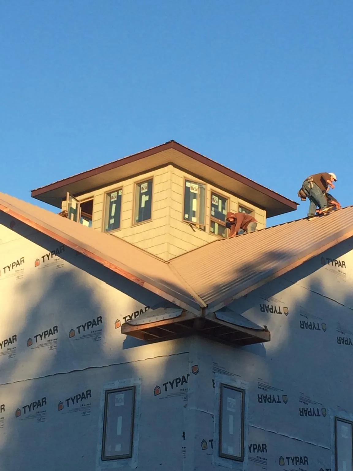 Roofers working around a rooftop cupola on a new metal roof at sunset — Roof Waterproofing in Little Orleans by Roofing Brothers